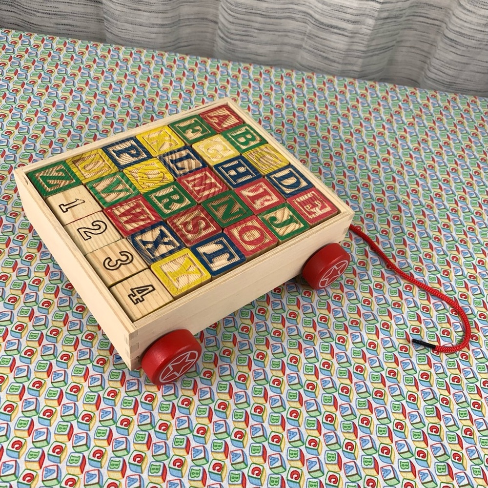 Alphabet Wood Block Pull Cart Toy with Red Wheels.